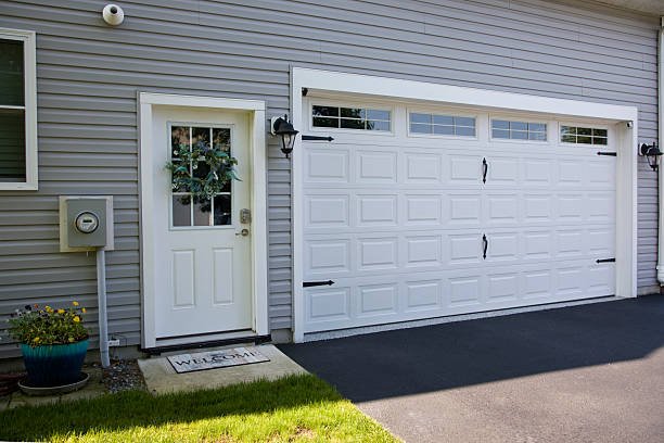 Suburban home exterior side door entrance and two car garage door in white.